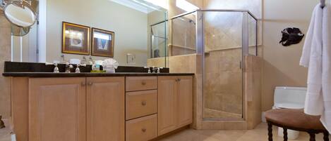 A modern bathroom with a large mirror, wooden cabinets, a glass shower enclosure, and a white toilet.