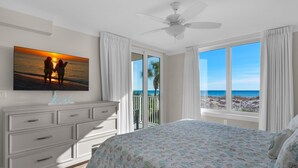 A bedroom with a bed, a dresser, a ceiling fan, and a large window with a view of the beach. - 🌊BEACH Front Corner Unit~Free Beach Service~Pool~3BR Island Princess 200🌅 (Fort Walton Beach)