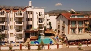 Un hôtel à plusieurs étages doté de balcons, d’une piscine et d’une structure surmontée d’un toit de chaume.