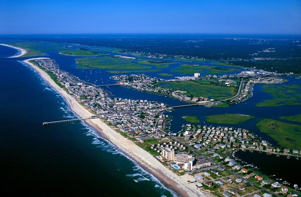 An aerial view of a coastal town with a beach, marina, and residential areas.