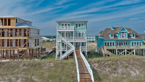 A coastal house under construction with a wooden staircase leading to a multi-level deck. - Endless Summer by GSVR | 7BR Beachfront Home w/ Pool & Handicap Access + FREE Activities/Golf (Gulf Shores)