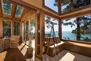 A sunlit room with large windows, wicker furniture, a telescope, and a view of the ocean. - Sea Cliff - Perched above Sea, Romantic & Private! (Trinidad)