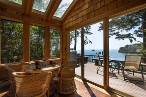 A sunlit room with large windows overlooking a deck and ocean. - Sea Cliff - Perched above Sea, Romantic & Private! (Trinidad)