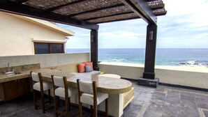 A kitchen with a bar area, a sink, and a view of the ocean.