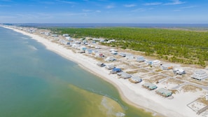 Vue aérienne d’une zone côtière avec des maisons de plage et une route qui longe le rivage.