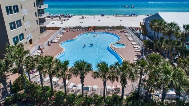 A resort with a large pool, a beach, and a view of the ocean.