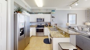 A modern kitchen with white cabinets, stainless steel appliances, a granite countertop, and a built-in oven.