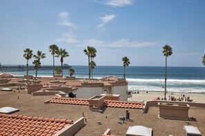 Un hotel frente a la playa, con techos de tejas, palmeras y vistas al océano.