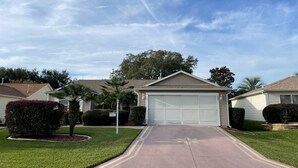 A residential driveway leading to a garage with a clear sky above. - Chic Gem in The Villages - Modern Amenities & Prime Location! Call today! (The Villages)