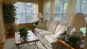 A living room with a sofa, two lamps, a coffee table, and a potted plant. - Chic Gem in The Villages - Modern Amenities & Prime Location! Call today! (The Villages)