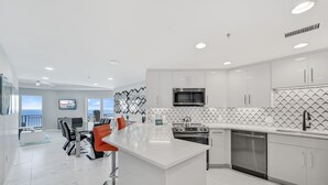 A modern kitchen with white cabinetry, a stainless steel microwave, and a built-in oven. - Fully Remodeled Modern Condo ~ Golf Cart (Miramar Beach)