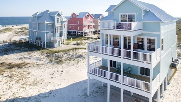 A beachfront property with multiple-story buildings featuring balconies and a sandy beach in the background. - Grace | 6BR Fort Morgan Beach Retreat | Pet-Friendly | Gulf View (Gulf Shores)