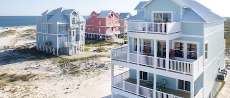 Propiedad frente a la playa con edificios de varios pisos, balcones y una playa arenosa de fondo.