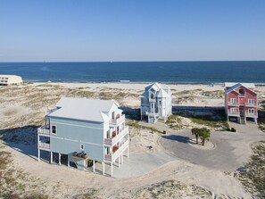 A beachfront property with three distinct buildings, a sandy beach, and the ocean in the background.