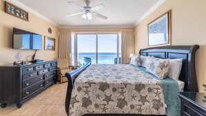 A bedroom with a bed, dresser, and a large window. - Boardwalk 1111 4BR/3BA PCB Beachfront Luxury (Panama City Beach)