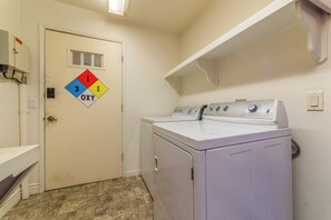 Une buanderie équipée d’un lave-linge, d’un sèche-linge et d’une porte sur laquelle est apposé un panneau indiquant les consignes de sécurité incendie.