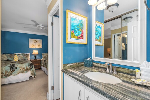 A bedroom with a bed, nightstand, lamp, and a large window. - Kamaole Nalu 106-Unbeatable Proximity to the Shore & Unbelievable Locale Await (Kihei, Maui)