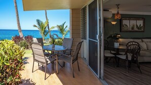 A balcony with a table and chairs, a sofa, and a view of the ocean.