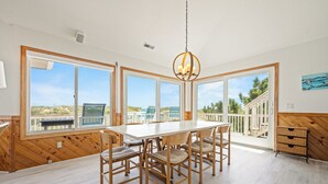 A spacious dining area with a large table and chairs, large windows with a view of the outdoors, and a wooden ceiling. - Time To Coast: Semi-Oceanfront, Hot Tub, Ocean Views (Corolla)