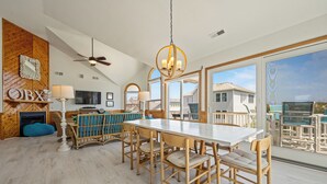 A spacious dining area with a high ceiling and large windows, wooden furniture, and a view of the surrounding neighborhood. - Time To Coast: Semi-Oceanfront, Hot Tub, Ocean Views (Corolla)