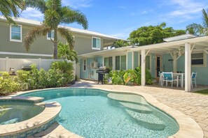 Piscina com hidromassagem, cercada por um terraço com móveis de exterior e uma área de estar coberta.