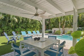 An outdoor patio with a pool, lounge chairs, and a table with chairs. - Ebb Tide by Duncan Real Estate (Holmes Beach)