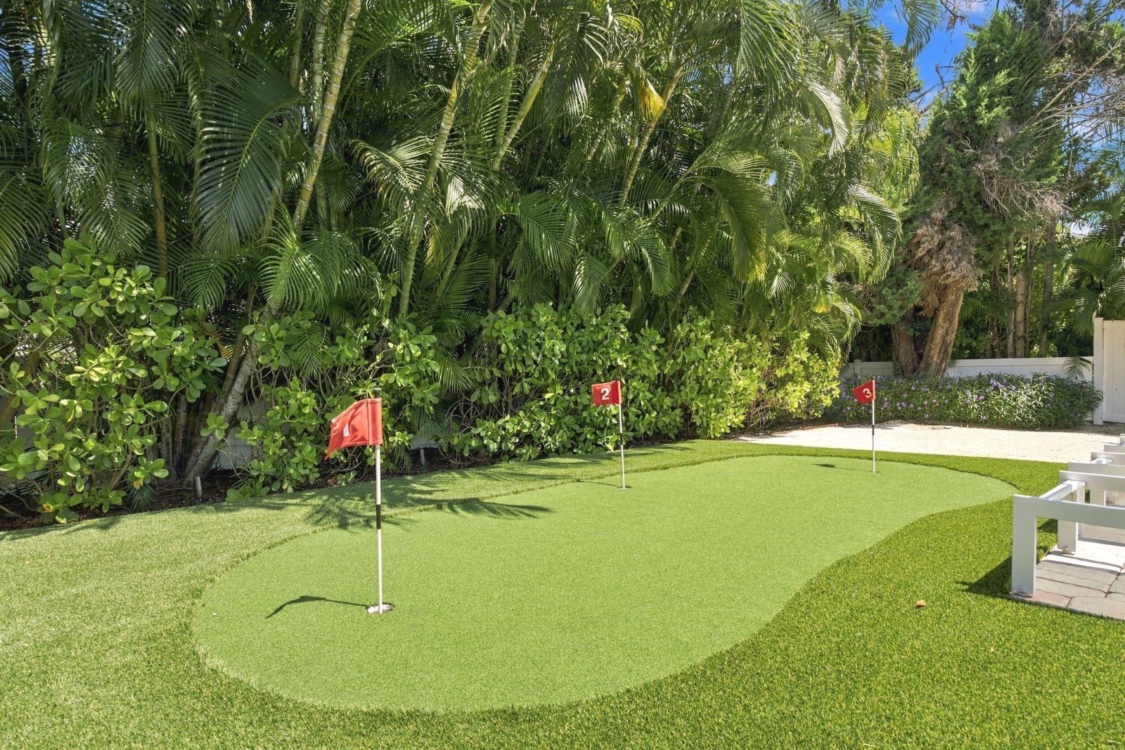 A well-maintained golf course with two flags marking holes 2 and 3, surrounded by lush tropical vegetation.