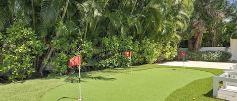 A well-maintained golf course with two flags marking holes 2 and 3, surrounded by lush tropical vegetation.