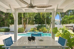 A covered outdoor area with a pool, a table with chairs, and a ceiling fan. - Ebb Tide by Duncan Real Estate (Holmes Beach)