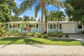 A two-story house with a garage, surrounded by a well-maintained lawn and various tropical plants. - Ebb Tide by Duncan Real Estate (Holmes Beach)