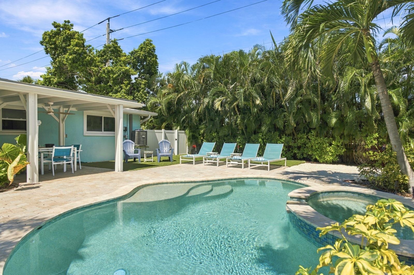 Ein Schwimmbecken mit Liegestühlen und einer überdachten Terrassenfläche.
