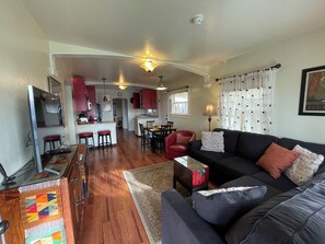 A spacious living area with a sofa, a dining table, and a kitchen in the background. - Potter's Bungalow - Near Downtown Plaza, 3 bed (Arcata)