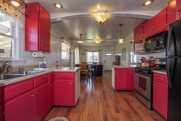A kitchen with red cabinets, stainless steel appliances, and a wooden floor. - Potter's Bungalow - Near Downtown Plaza, 3 bed (Arcata)