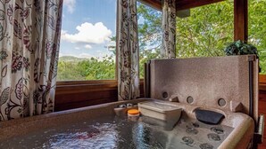 Un jacuzzi con reposacabezas de madera y vista a follaje exterior.