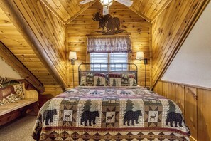 A cozy log cabin bedroom with a bed, two wall-mounted lamps, and a window with blinds.