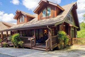 Une cabane en rondins avec un porche, une terrasse couverte et une cheminée.