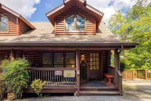 A log cabin with a porch, large windows, and a sign reading "Lucky Dogs". - Downtown Cabin w/Pool Table|Pool Access (PIGEON FORGE)