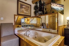 Une salle de bain avec un grand lavabo, des murs en bois et un miroir qui reflète une chambre à coucher avec un lit et un escalier.