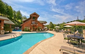 Une cabane en bois avec une piscine, un espace salon extérieur et une terrasse couverte.