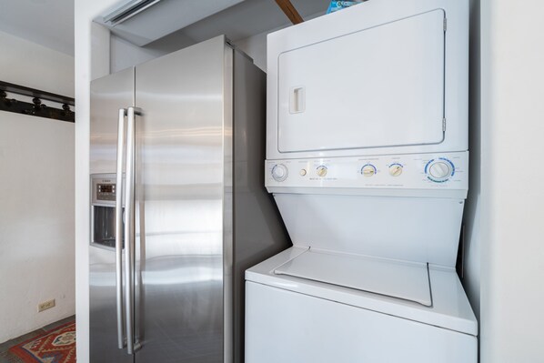 Cocina pequeña con refrigerador de acero inoxidable y lavadora blanca.
