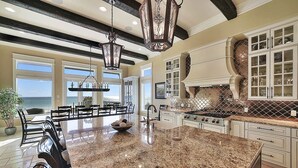 A spacious kitchen with granite countertops, a large island, and a view of the ocean. - Verona - Huge Ocean Front Home in Gulf Pines with Private Pool & Beach Access (Miramar Beach)