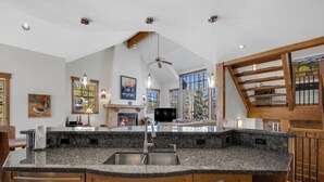 A kitchen with granite countertops, stainless steel appliances, wooden cabinets, and a large window with a view of trees. - Exquisite Spacious Breck Chalet. Walk to Slopes. Gourmet Kitchen. Large Deck (Breckenridge)
