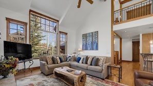 A spacious living room with a large sectional sofa, a wooden coffee table, and a television. - Exquisite Spacious Breck Chalet. Walk to Slopes. Gourmet Kitchen. Large Deck (Breckenridge)