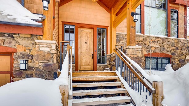 A stone and wood building with a wooden front door, a staircase with a wooden railing, and a stone wall. - Exquisite Spacious Breck Chalet. Walk to Slopes. Gourmet Kitchen. Large Deck (Breckenridge)