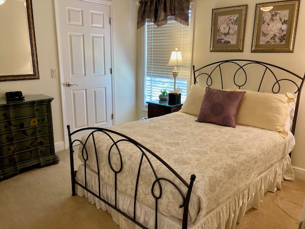 Une chambre à coucher avec un lit, une commode et une fenêtre avec des stores.