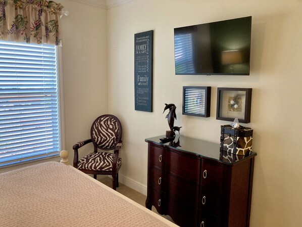 A bedroom with a bed, a chair, a dresser, a television, and wall decorations.