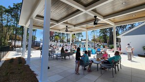 An outdoor patio area with a pool, seating, and a covered section. - Pet-friendly Fenced Yard, Linkside Village 476! (Destin)