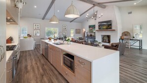 A spacious kitchen with a large island, wooden cabinets, and a modern stove.