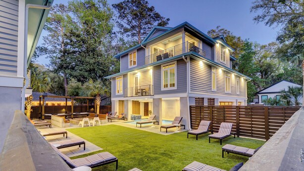 Een huis met twee verdiepingen, met een achtertuin, een zwembad, terrasmeubels en een houten terras.