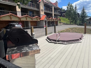 Een terras met een barbecue en een jacuzzi.